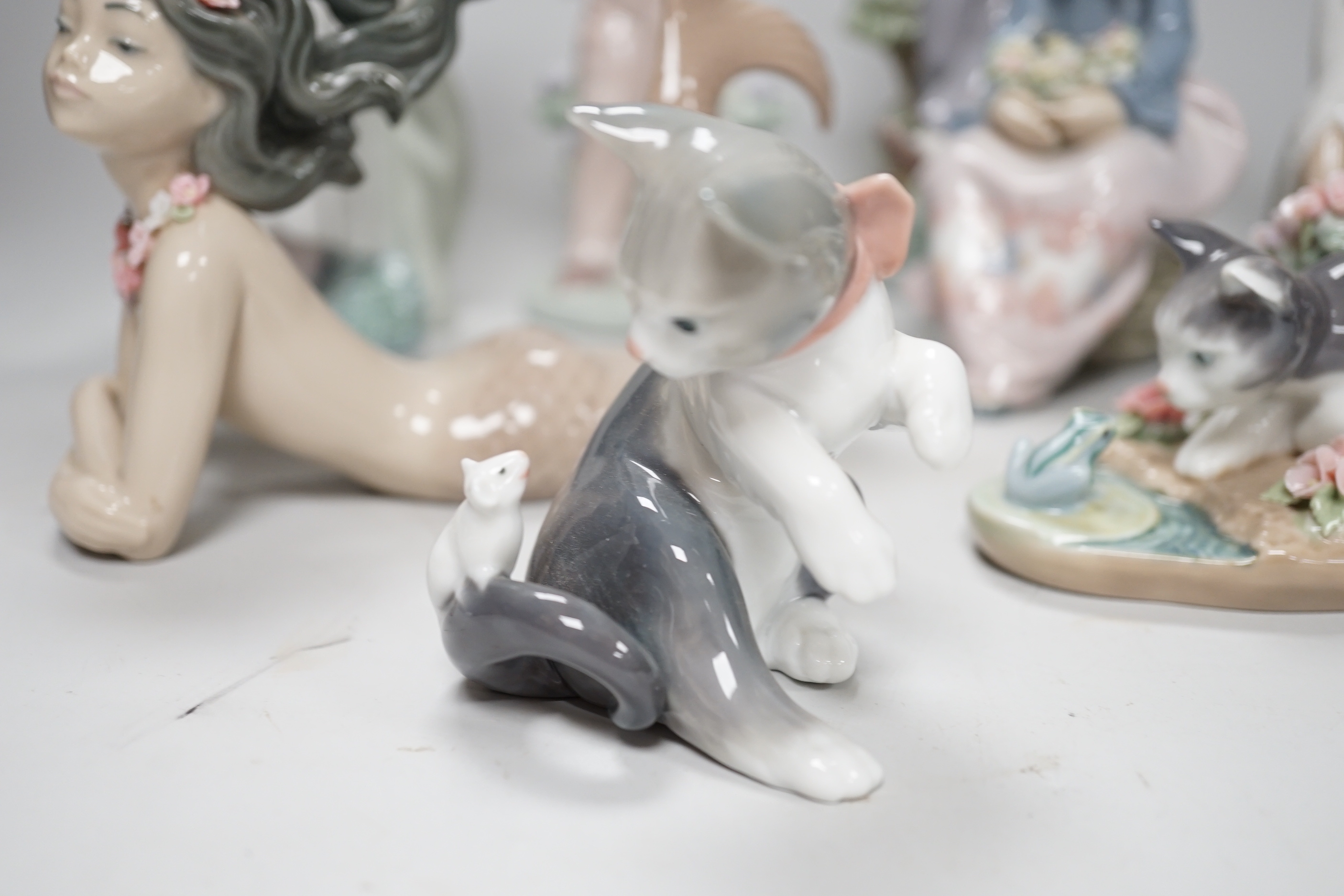 A large Lladro figure of a flower girl, mermaid, boy playing a drum and five other models including a Nao example, the largest 24cm high (8)